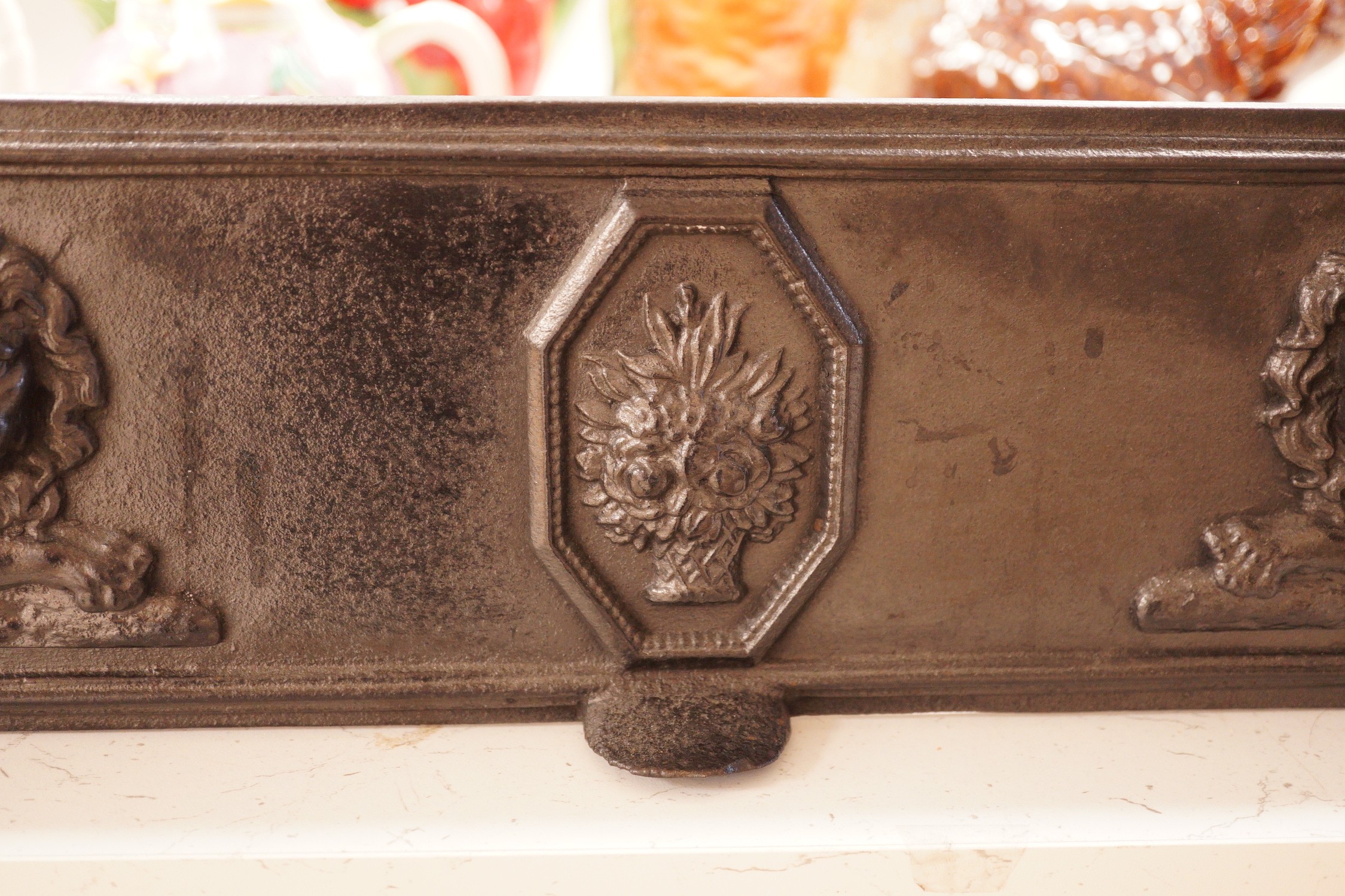 A blackened cast iron fender, of rectangular form decorated with lions, 76.5cm wide, 31cm deep